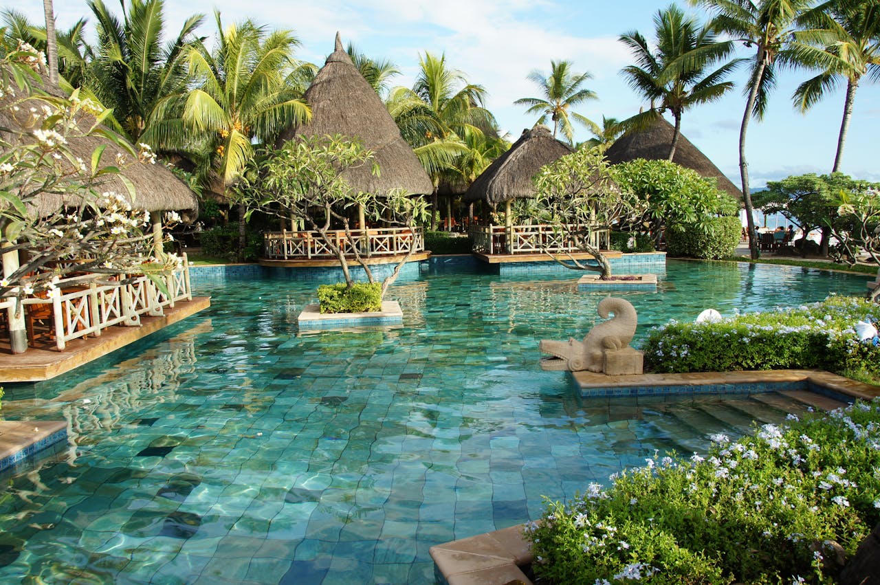 Resort grounds with pool, palm trees and guest pavilions